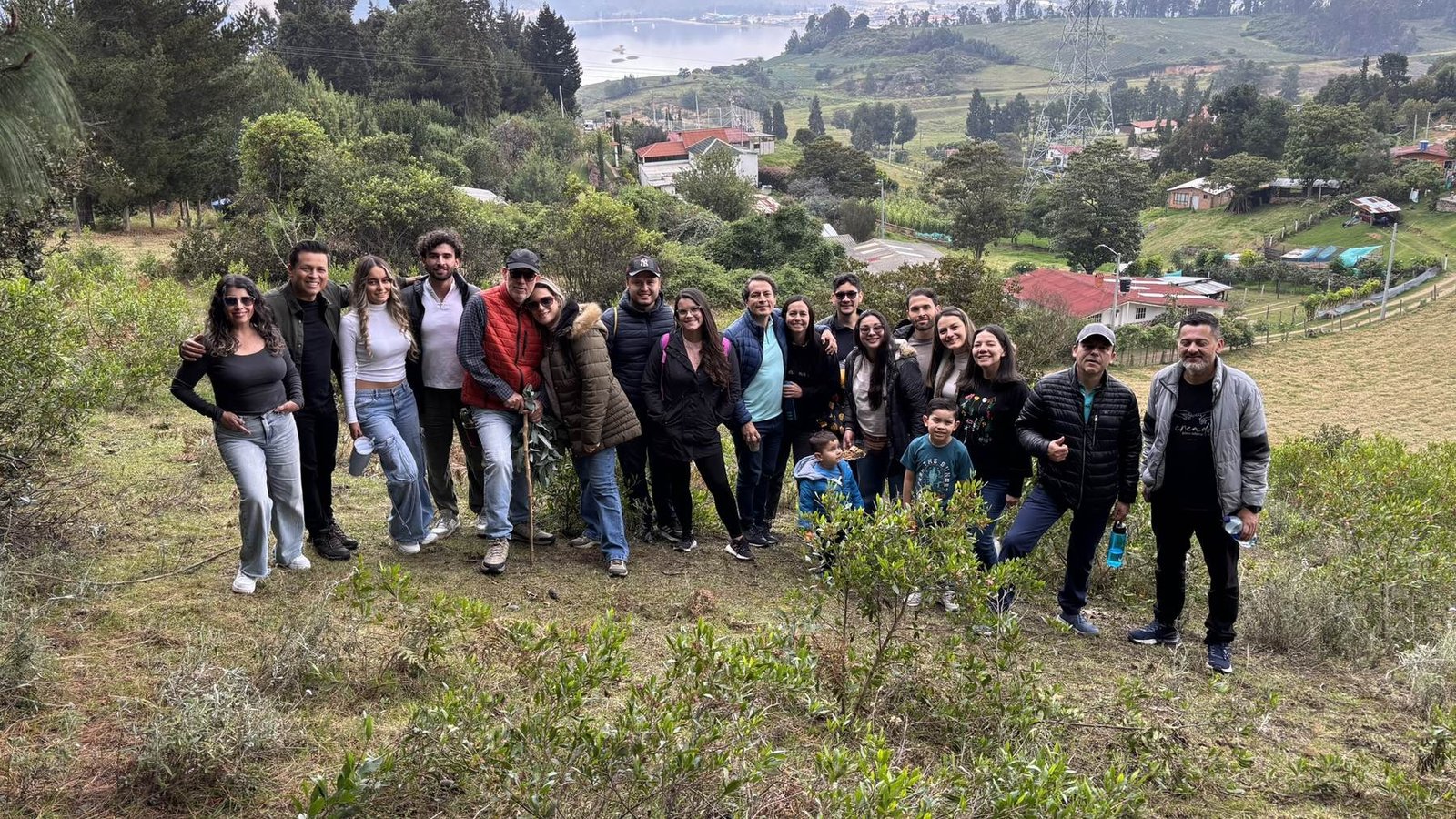 La comunidad de Nuevo Aire reunida en una salida al campo, con una laguna y montañas de fondo