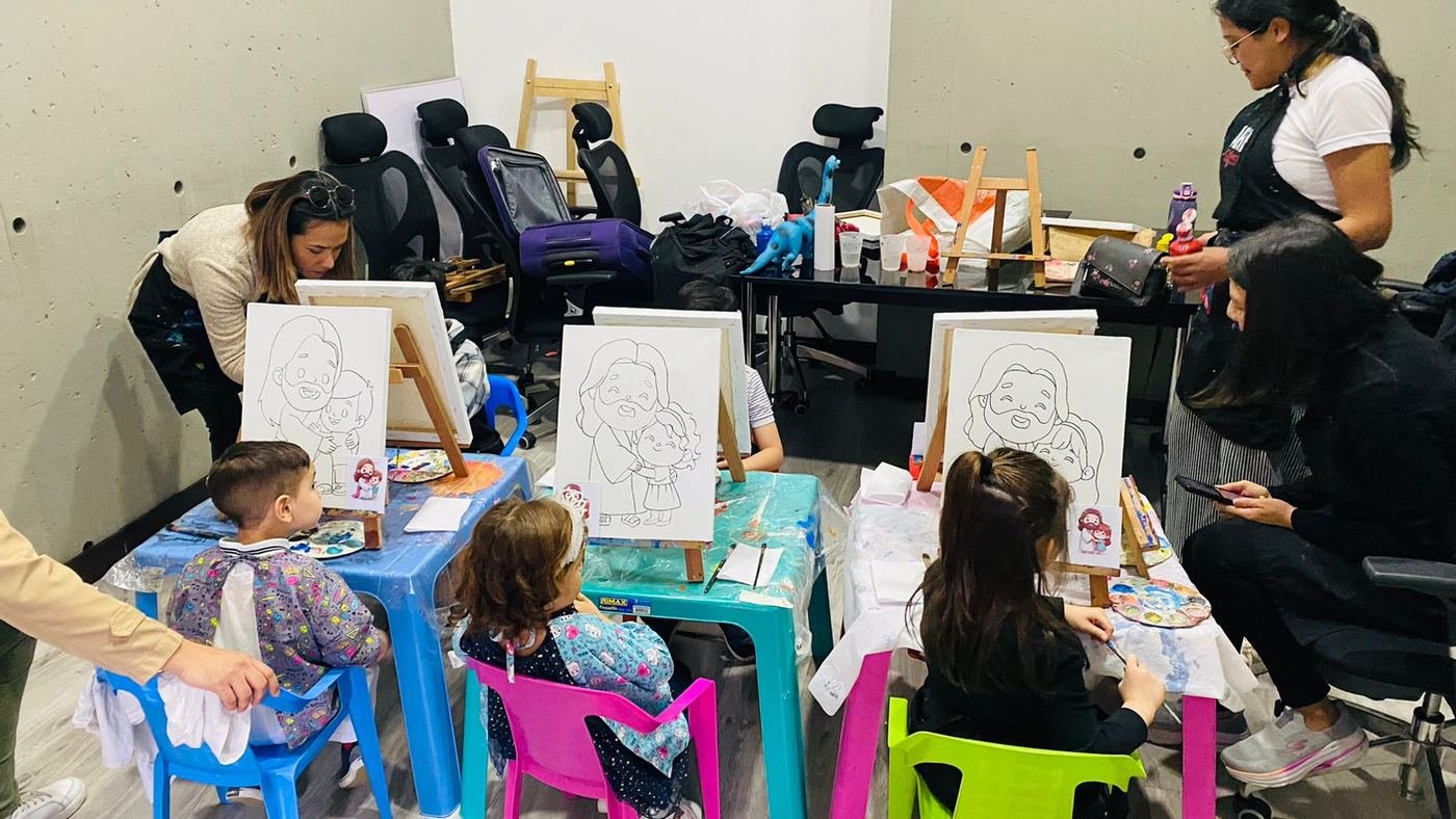 Niños pintando sobre lienzos en caballetes durante un taller creativo